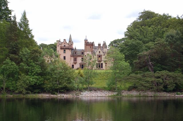 Aldourie Castle, seen from Loch Ness. Attribution: By John Allan, CC BY-SA 2.0, https://commons.wikimedia.org/w/index.php?curid=9428293