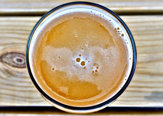 Glass of ale on wooden table, viewed from above Glass of ale on wooden table, viewed from above