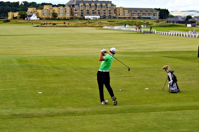 Man practicing his golf swing on the course at St. Andrews, Scotland