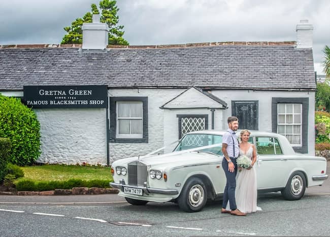 Just Married couple standing in front of Gretna Green Blacksmiths Shop in Scotland. Just Married couple standing in front of Gretna Green Blacksmiths Shop in Scotland.