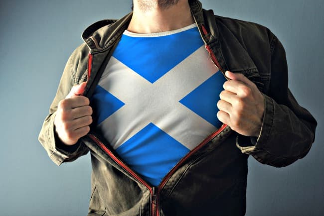 Hombre mostrando la bandera escocesa Saltire en una camiseta que lleva debajo de su chaqueta