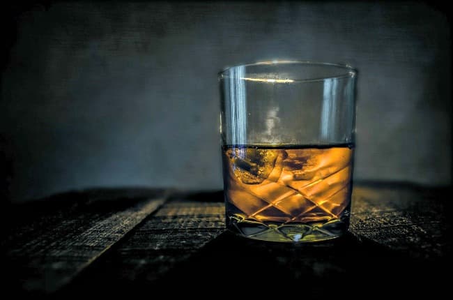 Vaso de whisky escocés con hielo en una mesa de madera